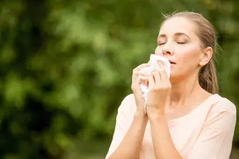 Hyposensibilisierung: Frau mit Heuschnupfen niest