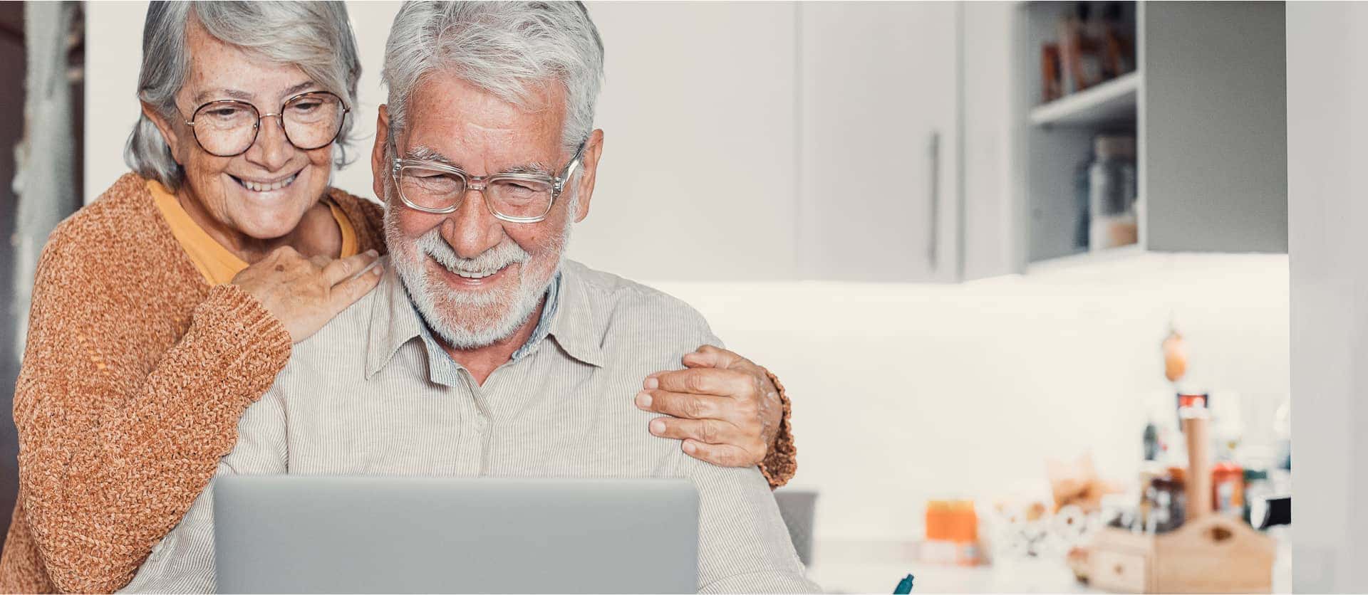 Seniorenpaar bei Recherche an ihrem Laptop2 Ein Seniorenpaar bei der Recherche an ihrem Latop in der Küche. Die Kamera ist von vorne auf das glückliche Paar gerichtet | TK Home Solutions