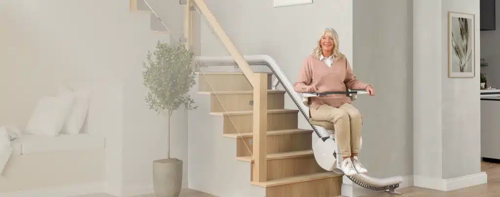 Header_Bild-aeltere-dame-sitzt-in-eingebautem-treppenlift Ältere Dame sitzt im Treppenlift und lächelt | TK Home Solutions