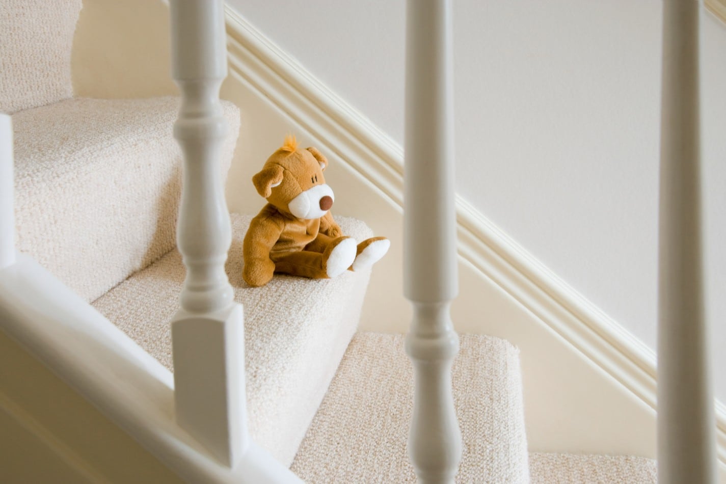 Ein Teddybär, der auf einer weißen Holzteppe sitzt.
