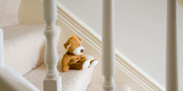 Symbolbild Treppe Header Ein Teddybär, der auf einer weißen Holzteppe sitzt.