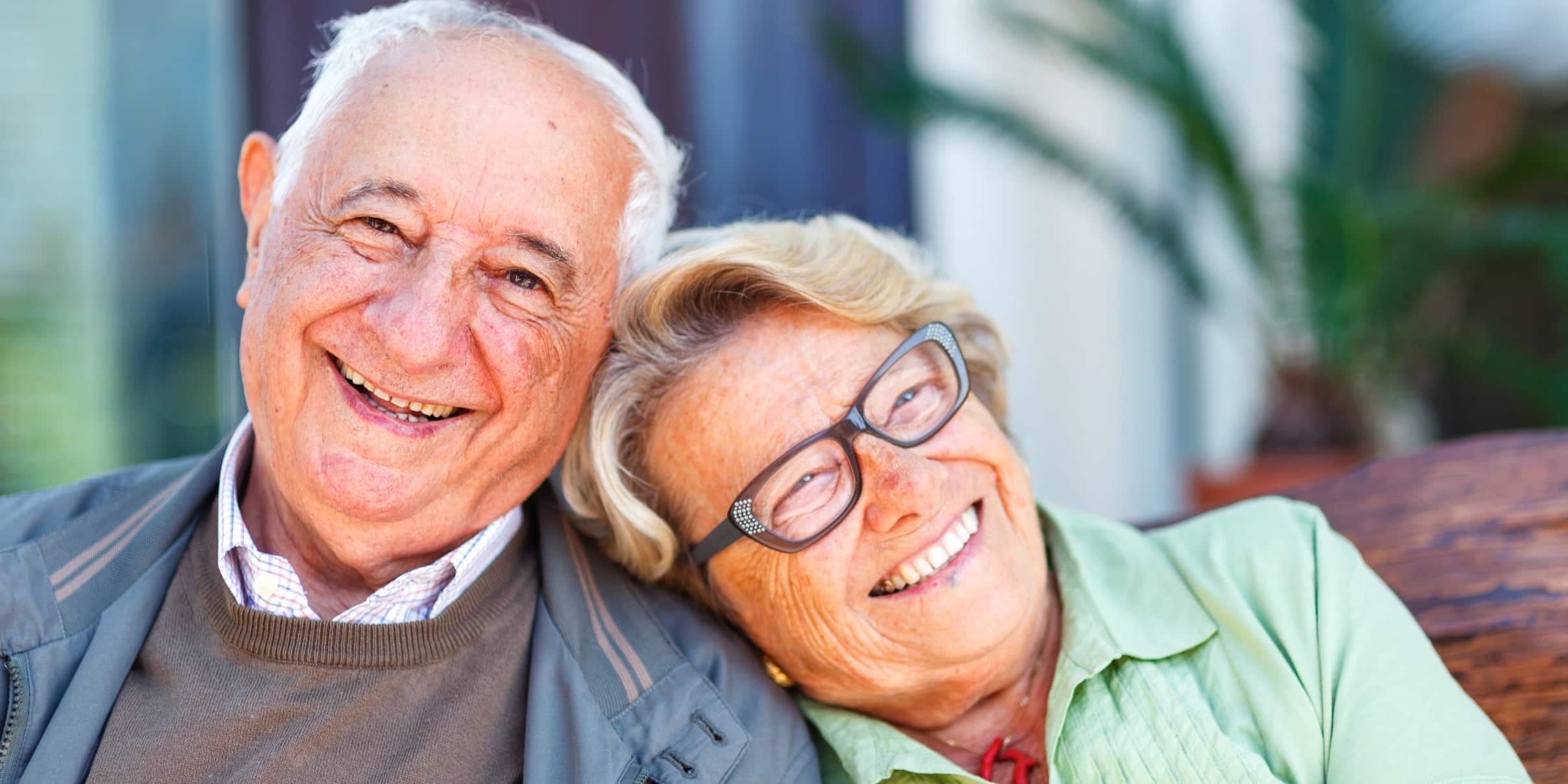 iStock-458251987 Cropped Ein älteres Ehepaar sitzt lachend aneinandergelehnt.