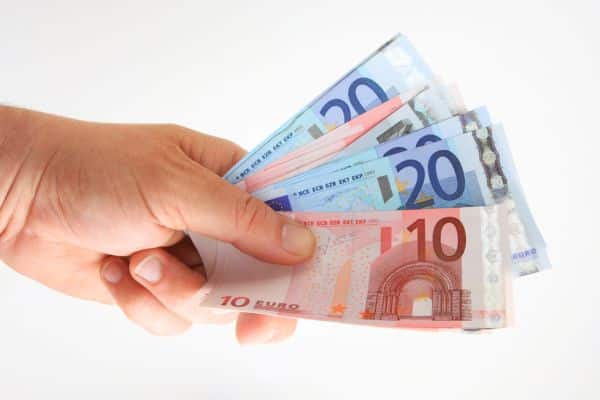 Symbolbild Geld Hand hält mehrere Euro-Banknoten (10- und 20-Euro-Scheine) vor weißem Hintergrund.