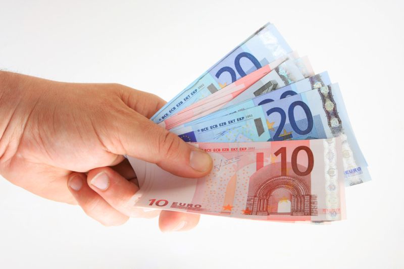 Symbolbild Geld Hand hält mehrere Euro-Banknoten (10- und 20-Euro-Scheine) vor weißem Hintergrund.