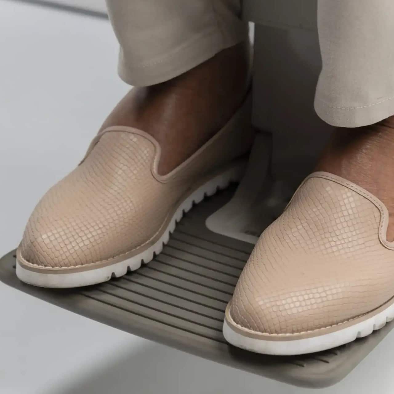 Nahaufnahme einer Person, die ihre Schuhe auf der Fußablage eines Treppenlifts ablegt.